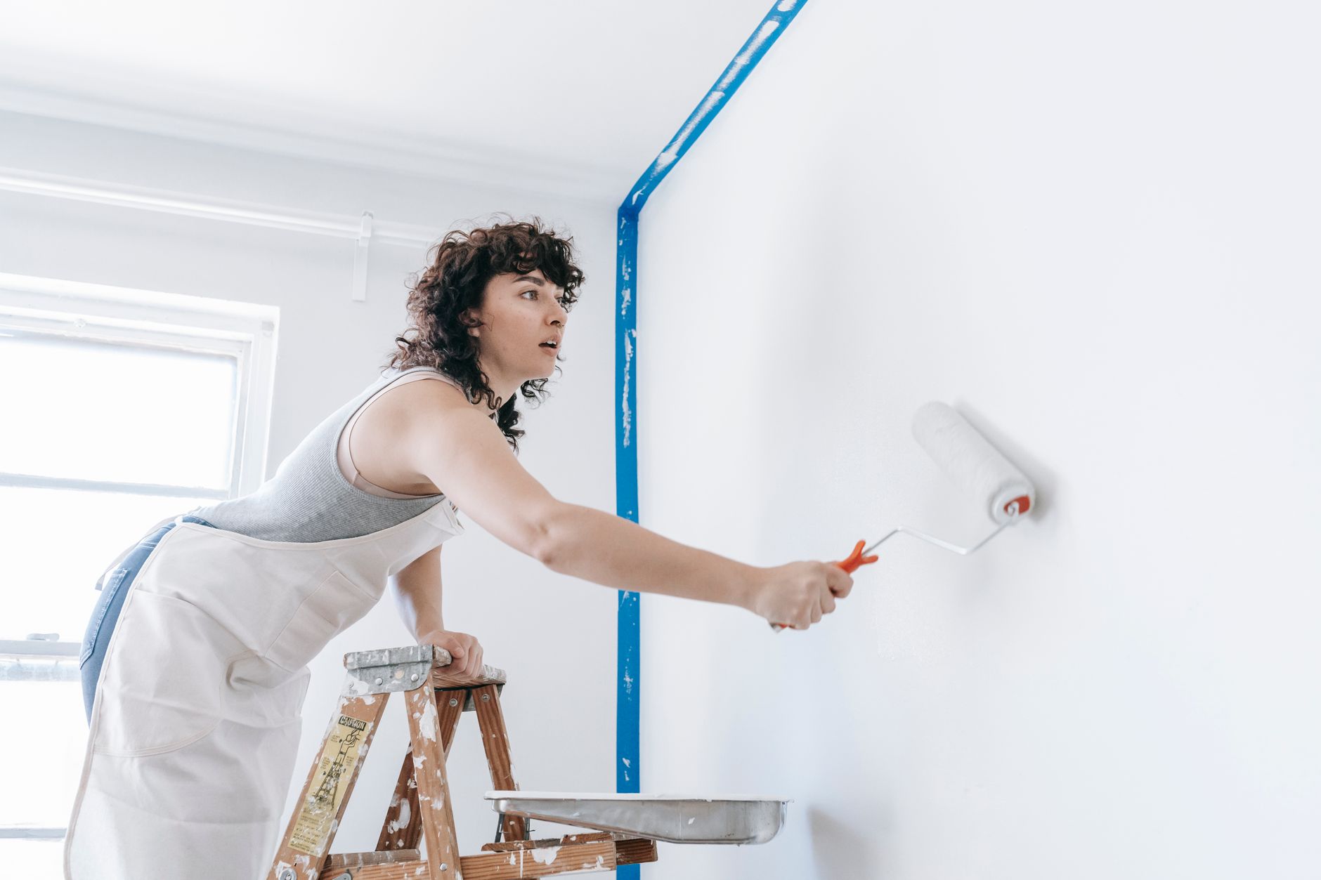 Person rolling white paint on an interior wall