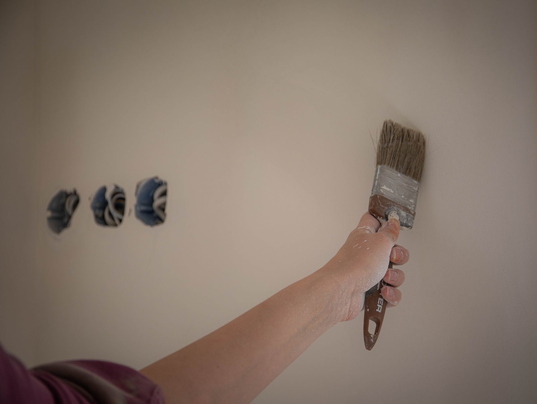 Person painting a wall with a brush